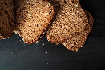 Flay lay photo of delicious fresh baked slices of bread with sunflower seeds on a dark table, horizontal image