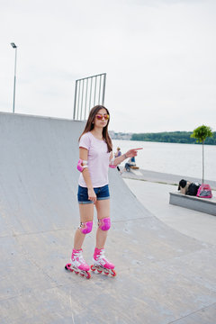 Portrait of a fabulous young woman rollerblading on the outdoor roller skating rink.