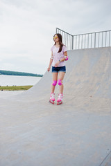 Portrait of a fabulous young woman rollerblading on the outdoor roller skating rink.