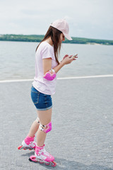 Portrait of a fantastic young woman roller skating with her phone in her hands in the park next to...