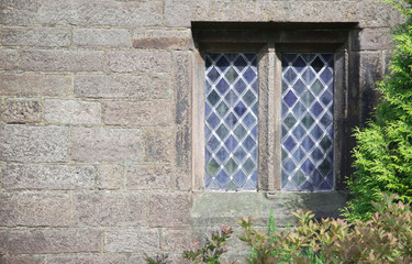 Fototapeta na wymiar Old leaded glass window in stone building