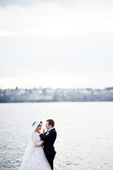 Newly married couple walking and posing on the lakeside on their wedding day.