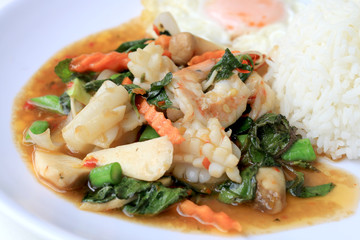 Asian food, Stir fried seafood with chili paste and basil leafs with rice on white plate, Spicy hot chilli Thai food.