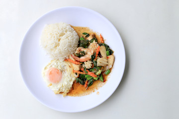 Asian food, Stir fried seafood with chili paste and basil leafs with rice on white plate, Spicy hot chilli Thai food.