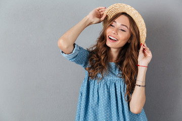 Happy young pretty woman standing over grey wall wearing hat