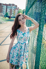 Beautiful young girl in a dress posing at the stadium