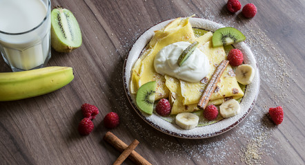 Homemade pancake with vanilla curd, raspberries, kiwi and banana pieces sprinkled with cocoa