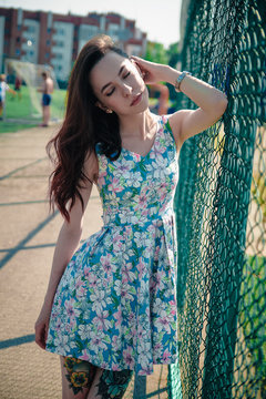 Beautiful young girl in a dress posing at the stadium