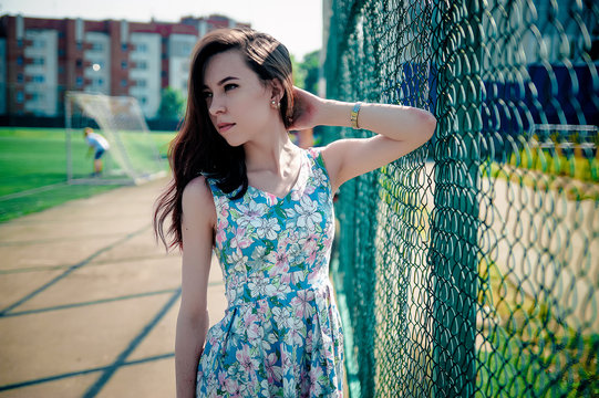 Beautiful young girl in a dress posing at the stadium