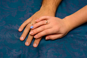 Photo of hands with beautiful wedding rings on blue background