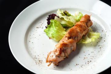 chicken kebab on a skewer with garnish and sauce
