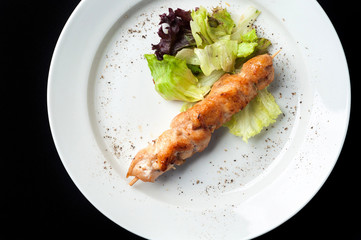 chicken kebab on a skewer with garnish and sauce
