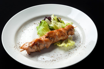 chicken kebab on a skewer with garnish and sauce
