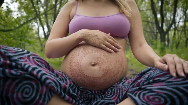 Pregnant girl with henna tattoo mehendi on her belly