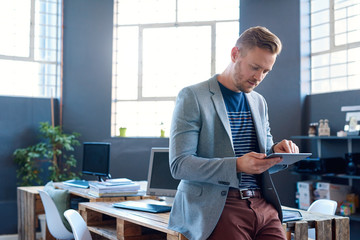 Focused young entrepreneur using a tablet in an office