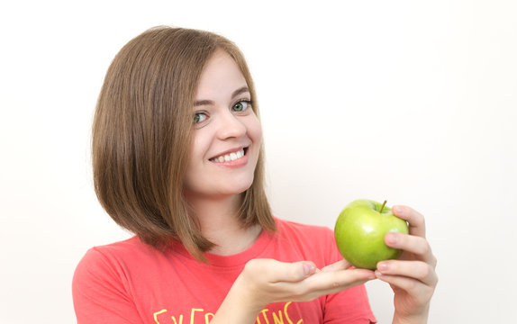 Portrait of smiling pretty girl with bob hairstyle and green apple in her hands as if suggesting healthy life, fruit diet or tasty apple. White background