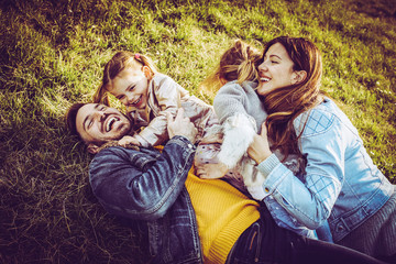 Happy family playing outdoor. Family lying and playing on the grass.