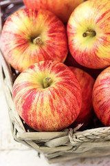 Heap of ripe organic red striped apples in a wicker basket. Whit