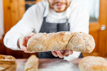 Baker man holding a beautiful fresh bread