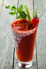 Glass of bloody mary on a wooden table. Delicious alcohol cocktail made of tomato juice, vodka, pepper, salt, lemon juice, celery and other flavorings. Close-up shot.