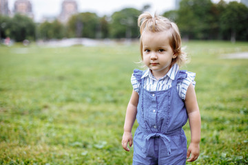 Beautiful happy little baby girl on a green meadow on the nature in the park