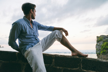 Fototapeta na wymiar Handsome man sitting on the beach and enjoying the view.