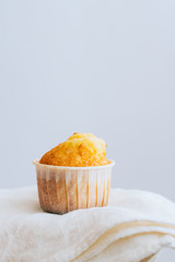Orange muffin on a white cotton napkin, on white, minimalism
