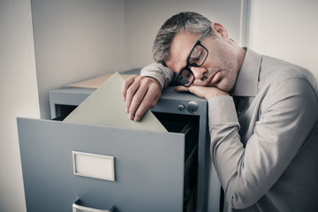 Tired office worker sleeping in the office - obrazy, fototapety, plakaty