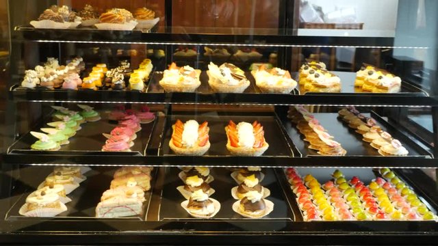Different types of cakes in pastry shop glass display 