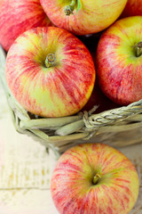 Heap of ripe organic red striped apples in a wicker basket and s
