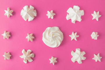White meringues on the pink background. Selective focus. Top view.