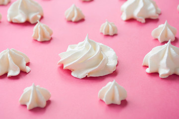 White meringues on the pink background. Selective focus.
