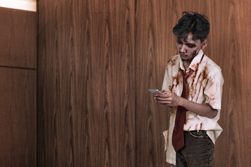 Spooky asian zombie man texting in his cellphone