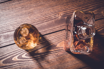 Whiskey bottle with whiskey glass on an old wooden table