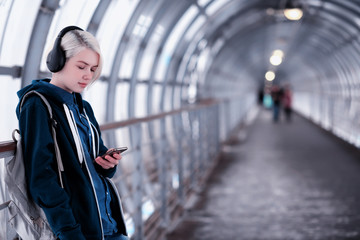 Fototapeta na wymiar Young student listening to music in big headphones in the subway tunnel