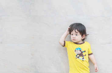 Closeup cute asian kid look at the space with confuse motion on marble stone wall textured background