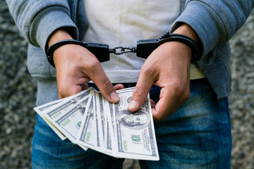 arrested rowdy in handcuffs counting dollar banknote. Arrested for attempting to bribe. Concept of...