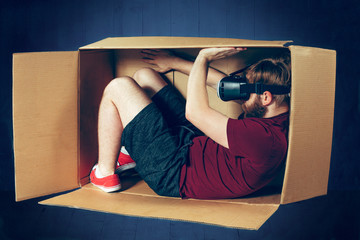 Introvert concept. The man sitting inside box with glasses of virtual reality. Future technology...
