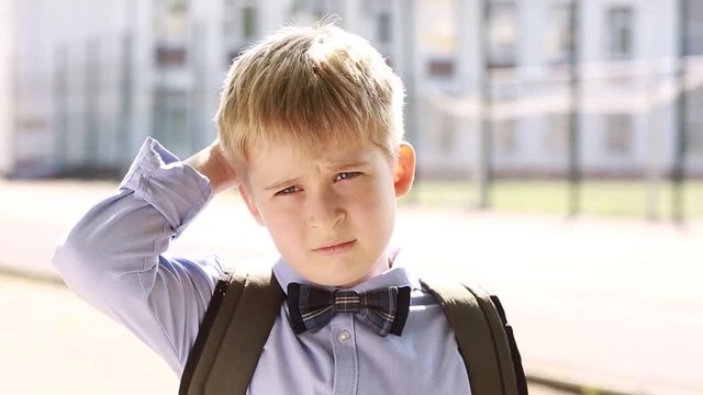 A frustrated child in the background of the school. A sad schoolboy. 