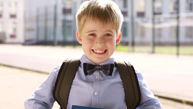 The child shows different emotions in the background of the school. A schoolboy with a book 