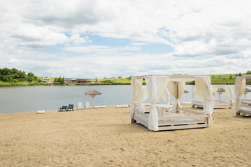 Sandy beach with pavilions, lake, cloud, sky