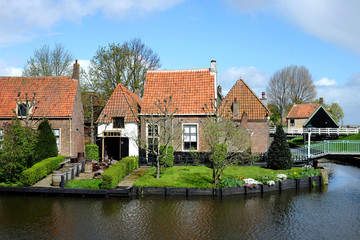 Red bricks house in countryside near the lake with mirror reflection in water