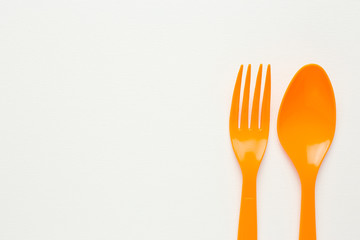 Orange spoon and fork on white canvas background
