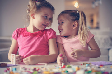 Fototapeta premium Girls playing at home. Girls playing with Bricks at home. Little girls having conversation.