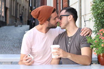 Gay couple about to kiss during a date at an outdoors cafe