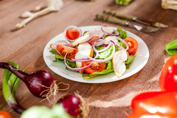 Fresh salad with chicken, tomato and greens on wooden background top view. Healthy food.