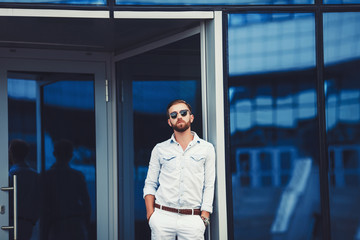 Fototapeta premium Stylish handsome man in shirt is posing next to a bright blue wall. Space for text