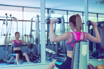 Beautiful girl exercising by lifting a dumbbell for health care in a public gym. Health care concept