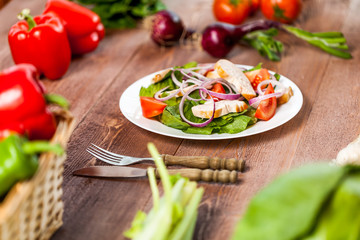 Fresh salad with chicken, tomato and greens on wooden background top view. Healthy food.