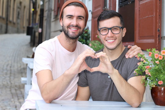 Beautiful homosexual couple creating a heart symbol 